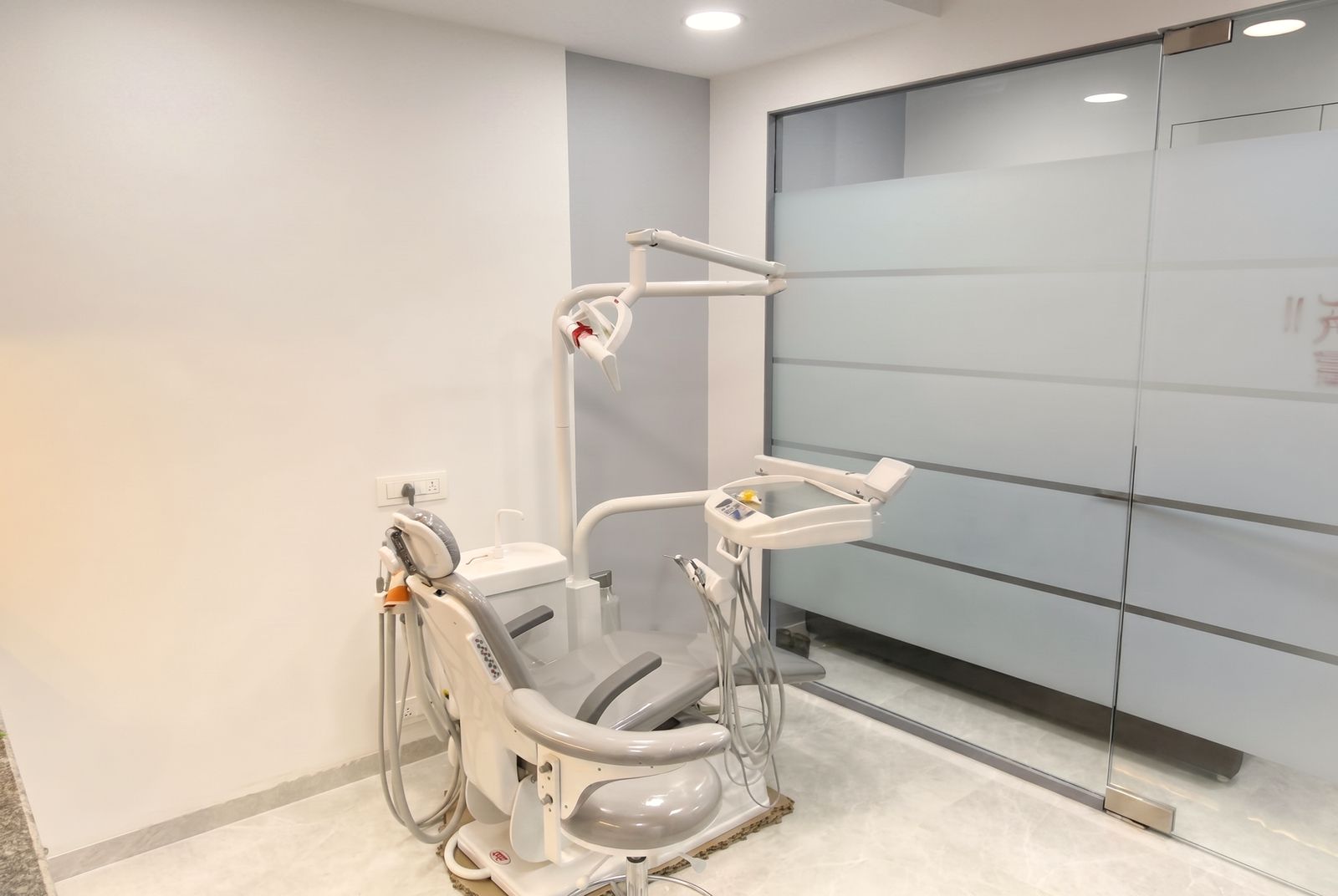 The treatment suite at Crown Dental Care with the dental chair, light and frosted glass wall